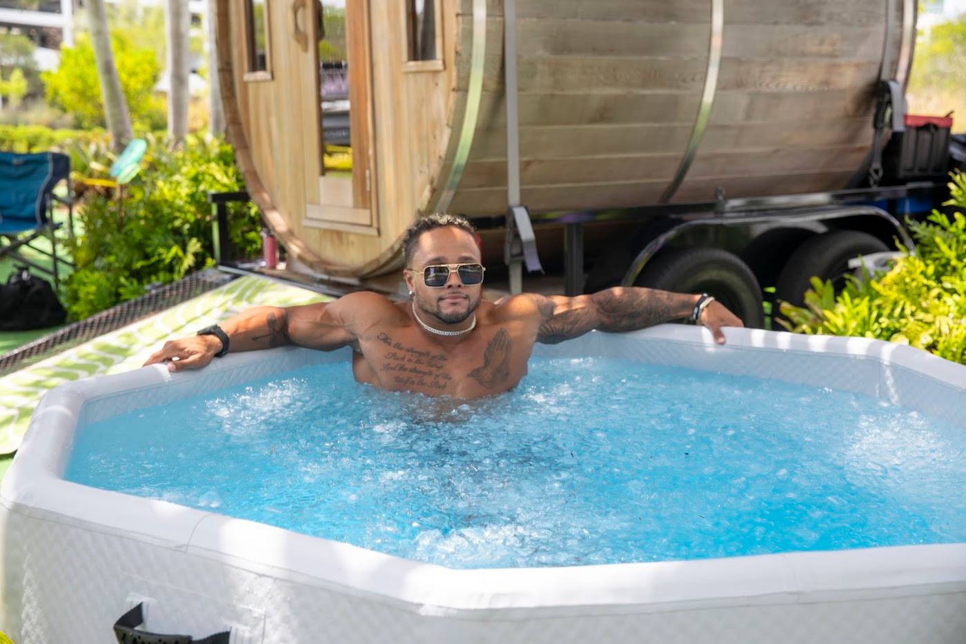 A guest in the cold plunge in front of the barrel sauna